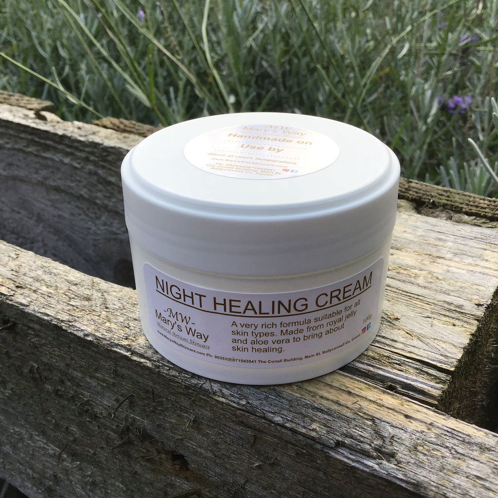 Jar of Marys way night healing cream resting on wooden pallet with foilage in background.