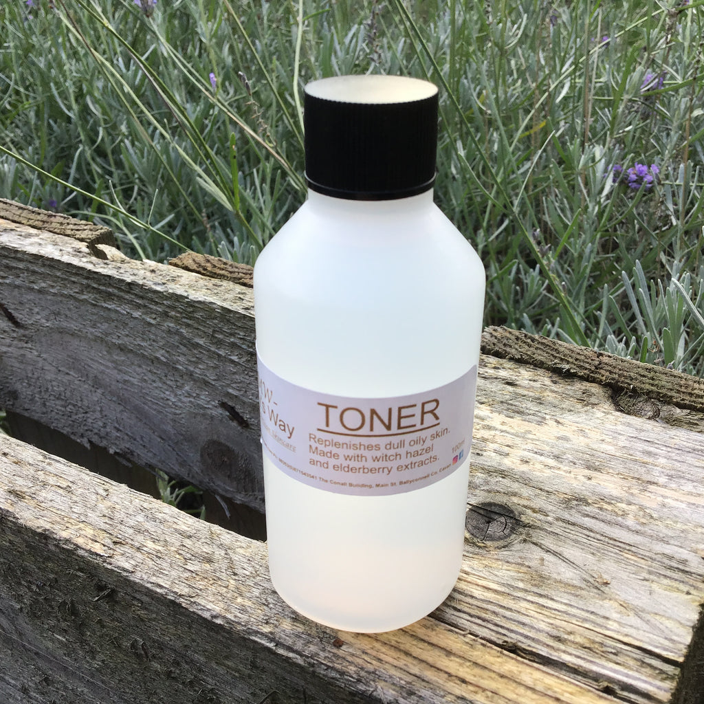Bottle of Mary's Way toner resting on wooden pallet with foilage in background.