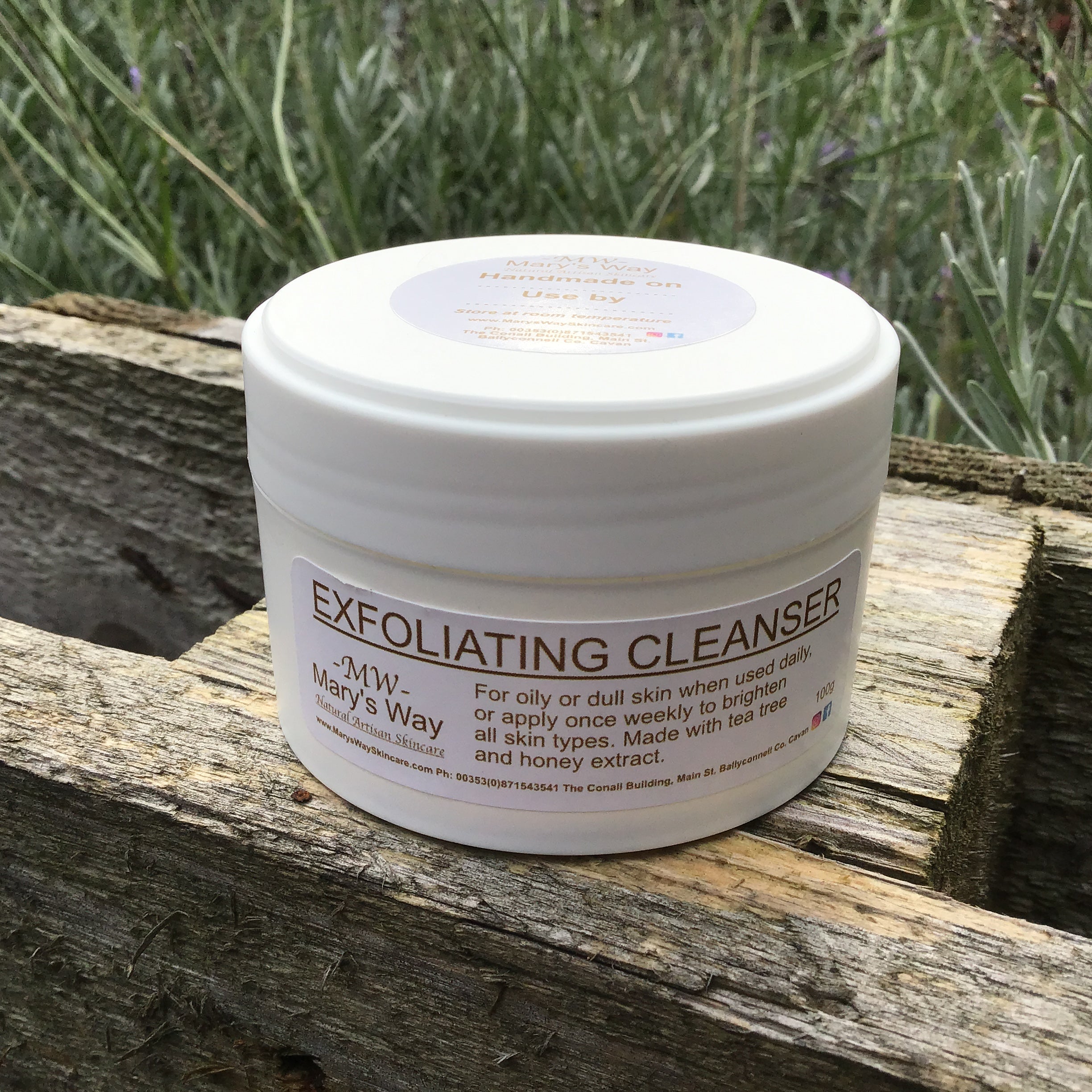 Jar of marys way exfoliating  cleanser resting on wooden pallet with foilage in background.